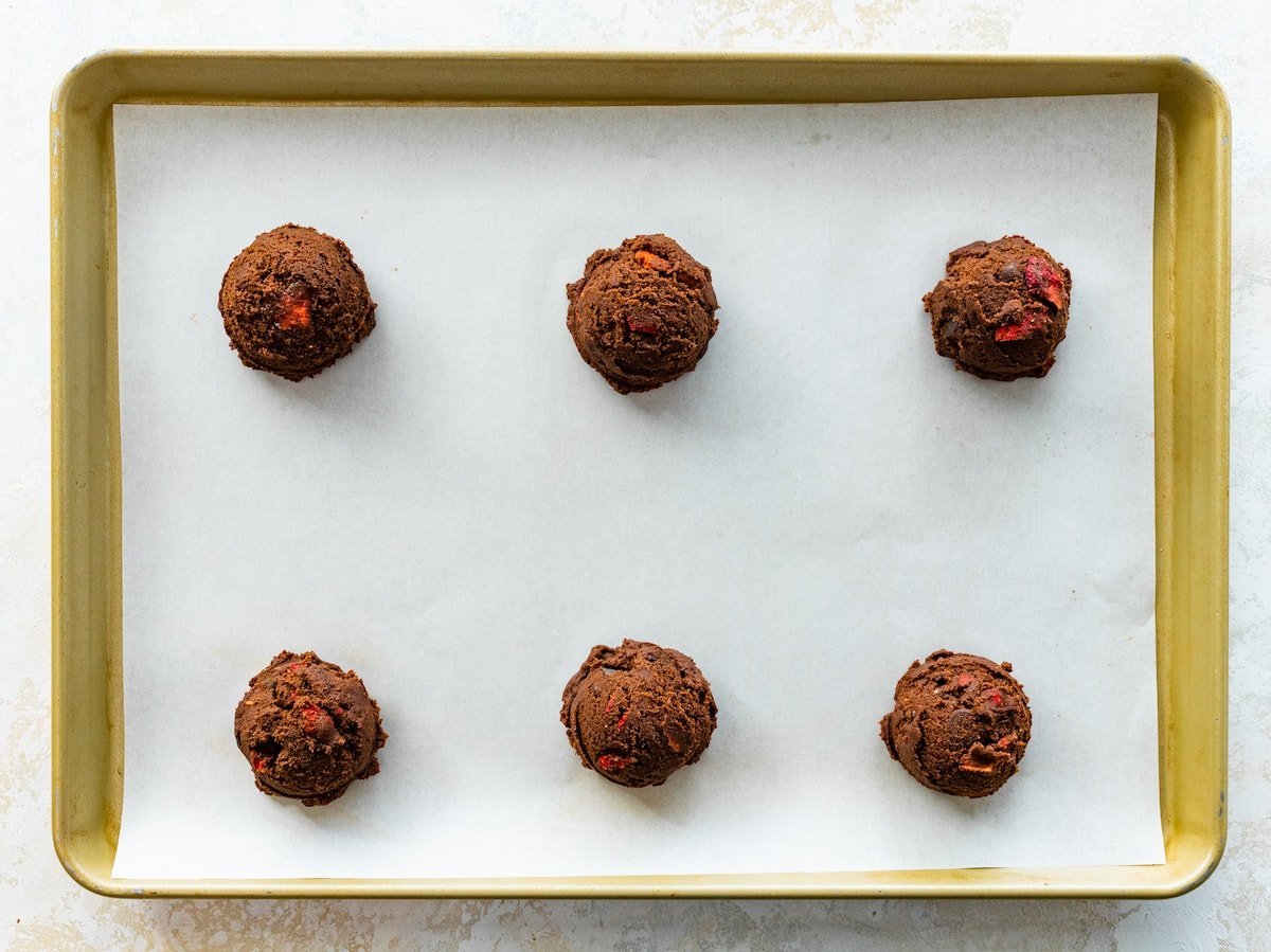 strawberry chocolate cookie dough balls on baking sheet with parchment paper.