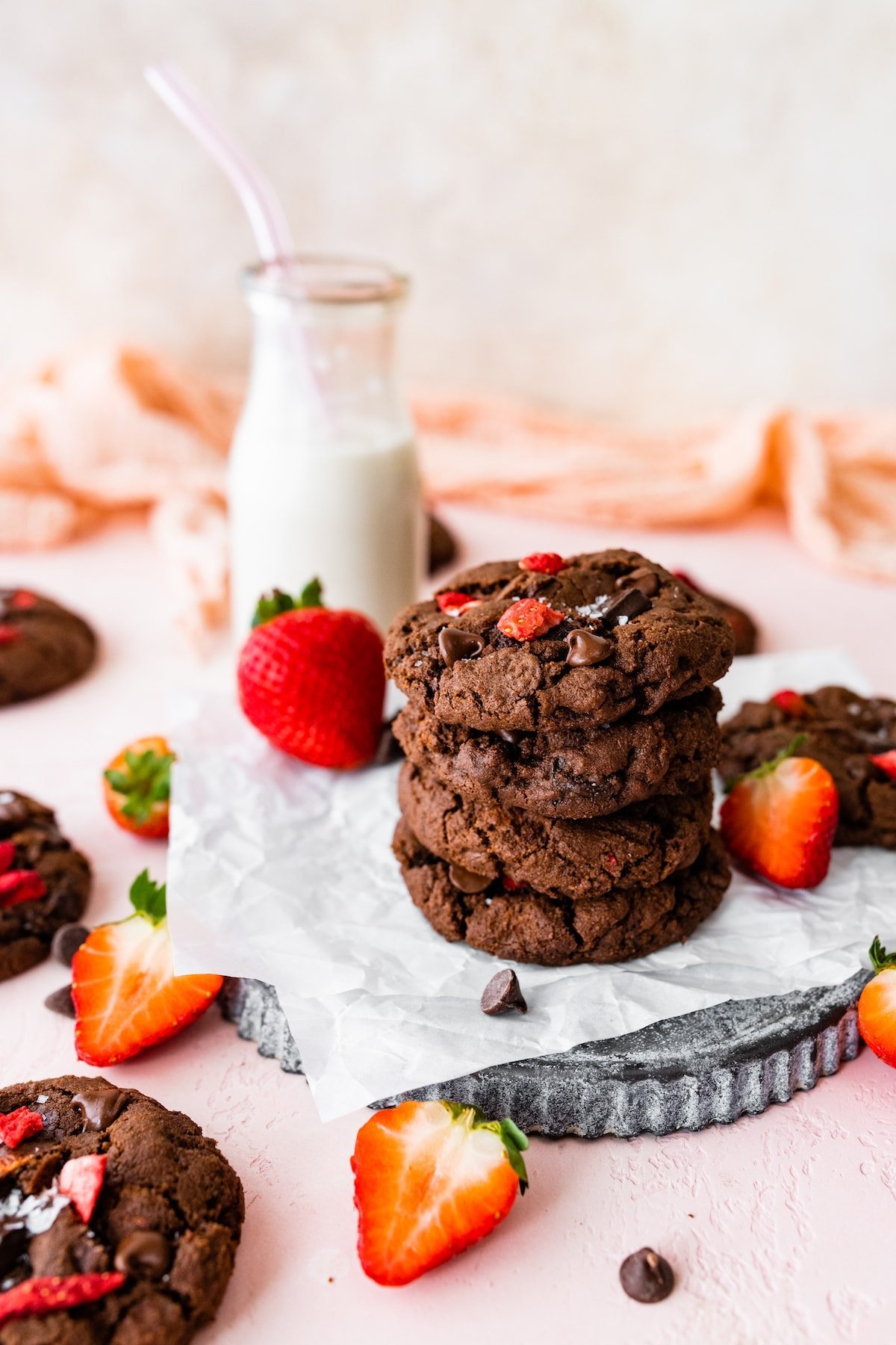 stack of strawberry chocolate cookies with bottle of milk.