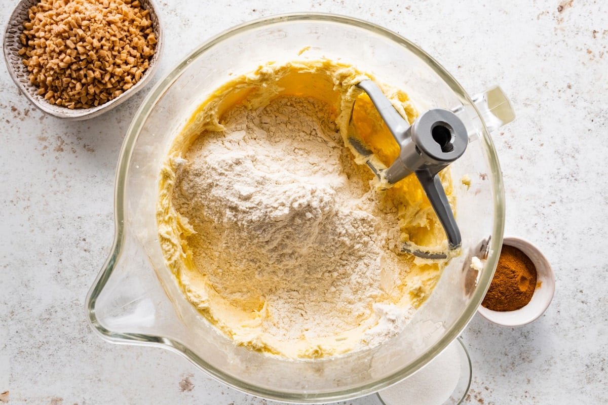 adding dry ingredients to butter mixture in mixing bowl.