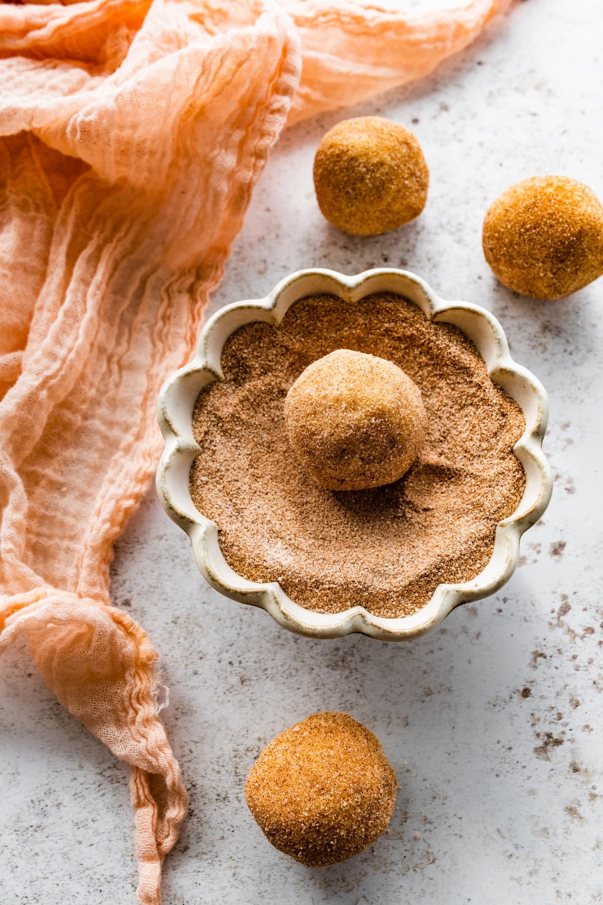toffeedoodles being rolled in cinnamon and sugar.