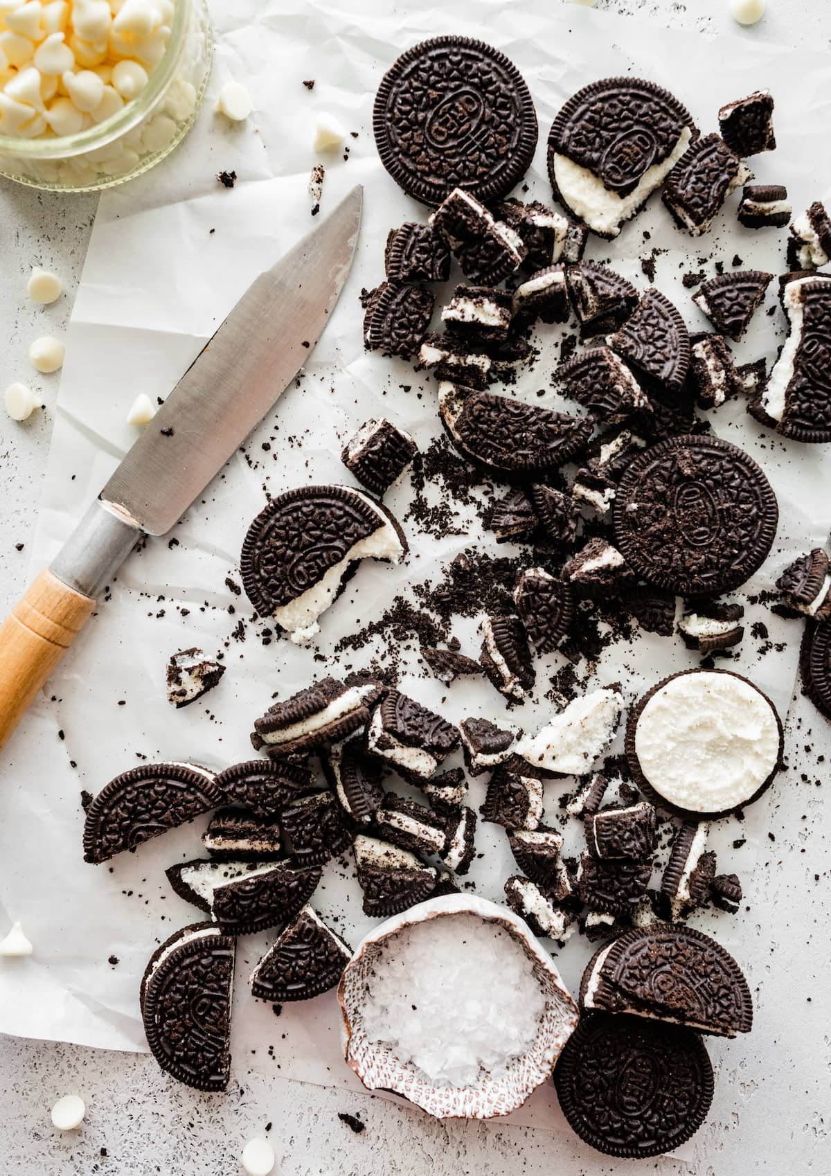 chopped up Oreo cookies on parchment paper with knife.