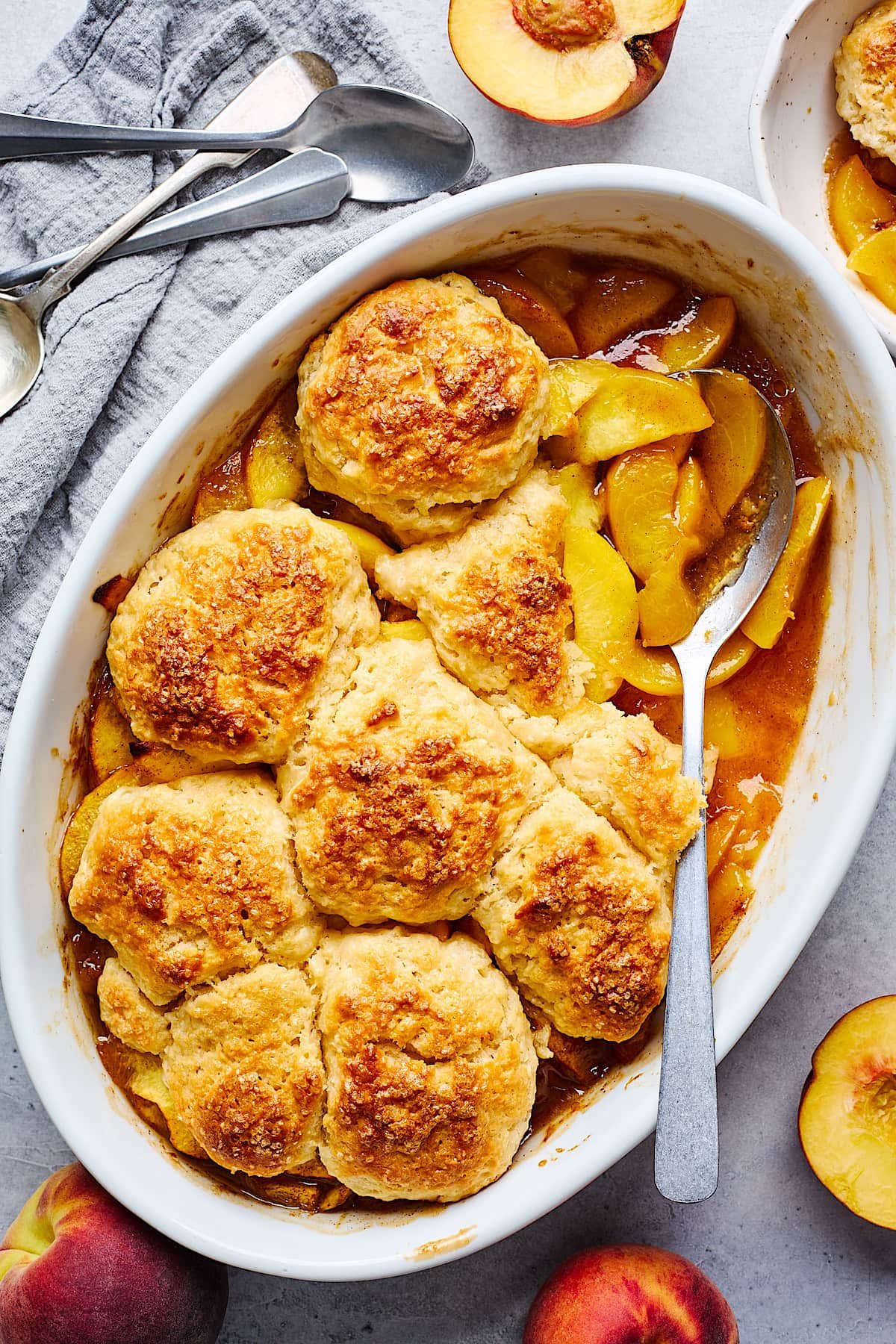 peach cobbler in baking dish with spoon.