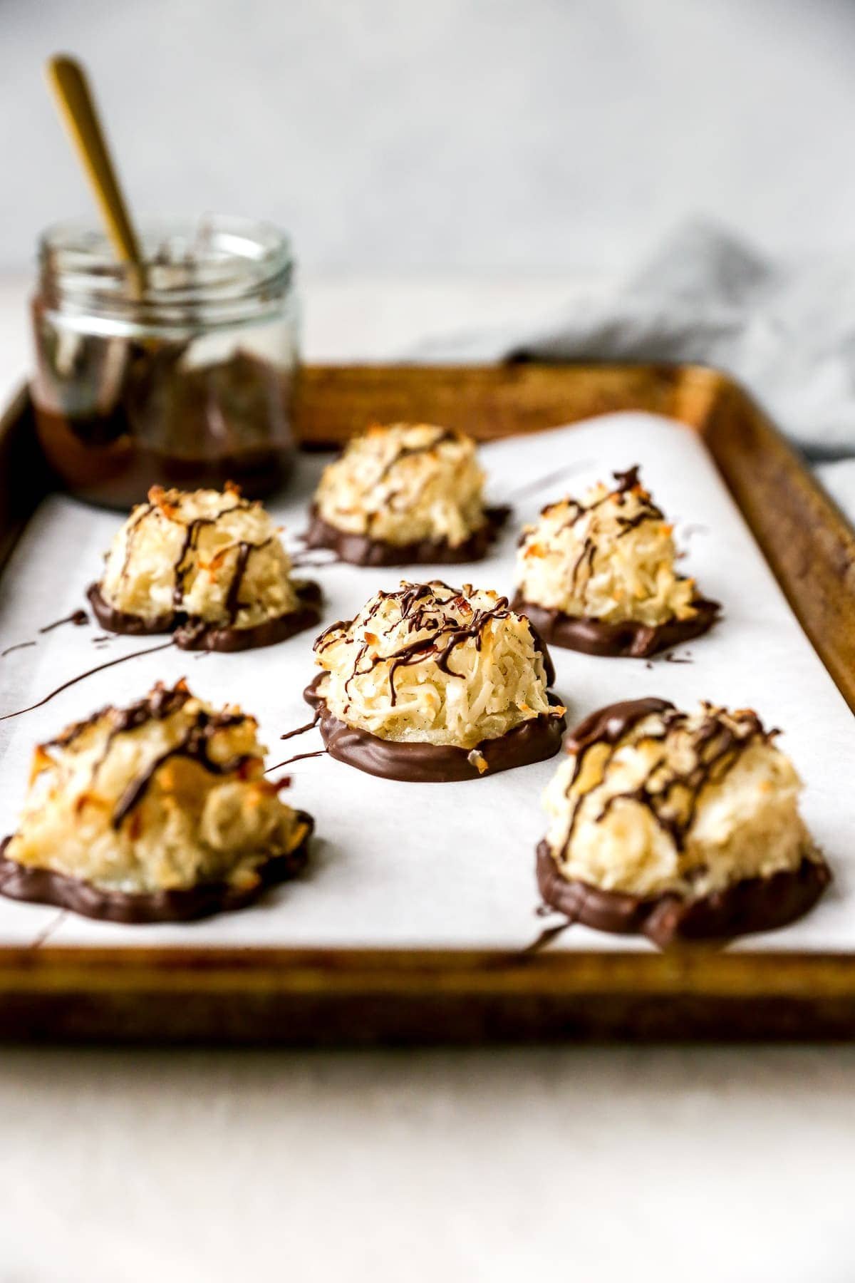 Coconut Macaroons dipped in chocolate on baking sheet with parchment paper.