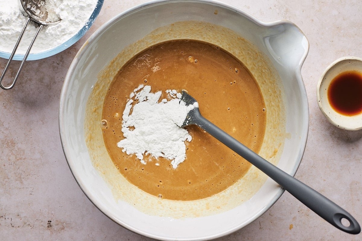 melted peanut butter fudge mixture in bowl with confectioner's sugar and spatula.
