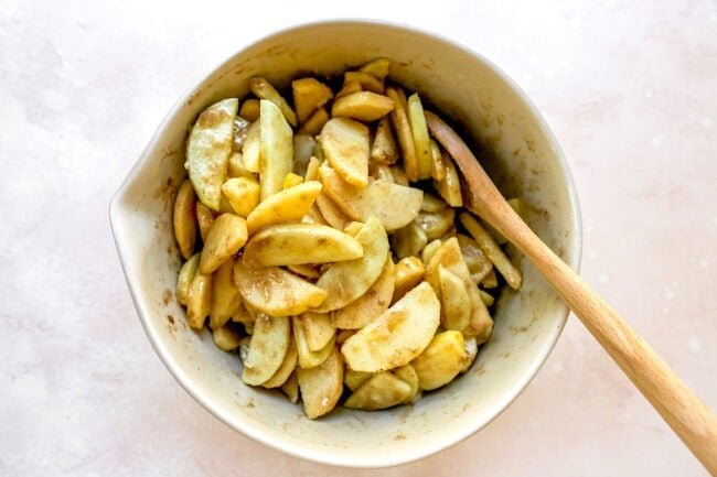 apple crumble filling in bowl with wooden spoon.