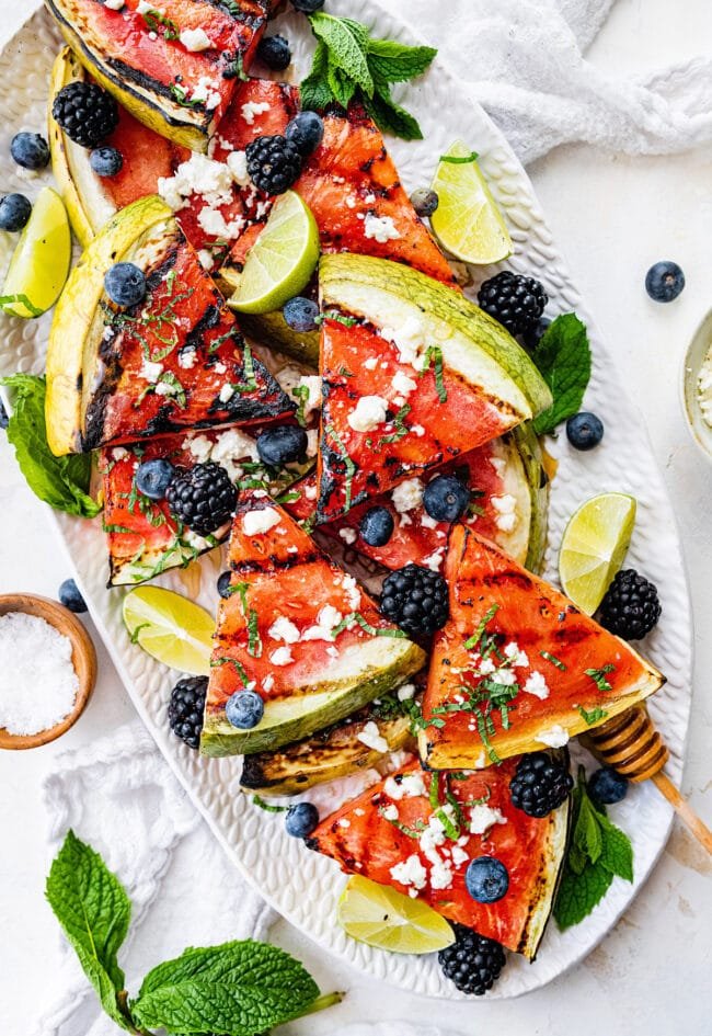 grilled watermelon wedges on platter with mint and berries.