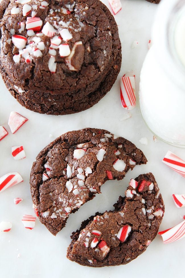 Chocolate Peppermint Crunch Cookie Recipe on twopeasandtheirpod.com Chocolate cookies with chocolate chips, peppermint crunch pieces, and candy cane pieces! These cookies are the PERFECT Christmas cookie! Chocolate Peppermint Crunch Cookie broken in half with candy cane pieces.
