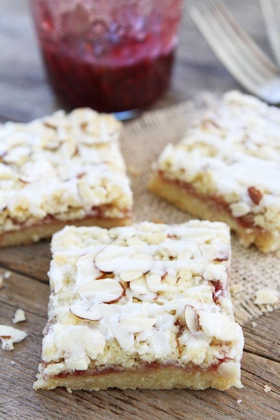 Raspberry Almond Shortbread Bars Recipe on twopeasandtheirpod.com Buttery shortbread bars with raspberry jam, almond streusel, and a sweet almond glaze! These bars are easy to make and always a hit! Raspberry Almond Shortbread Bars Recipe