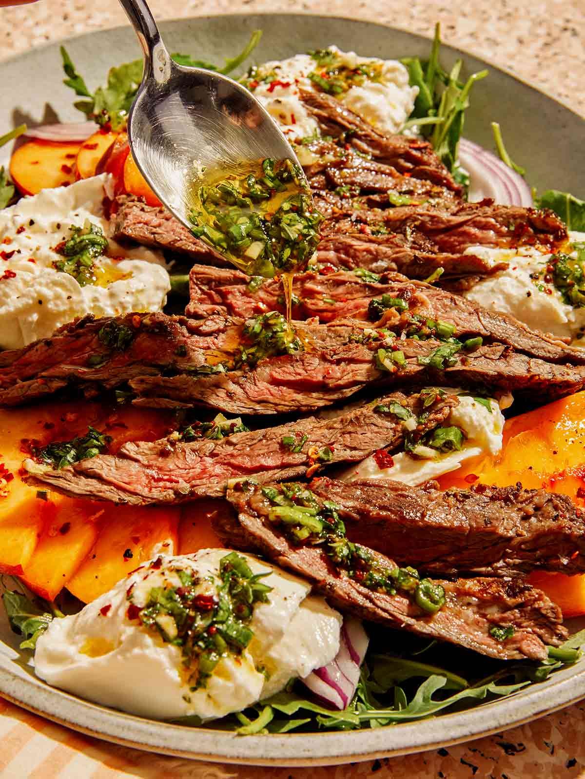 Grilled skirt steak salad with a dressing being poured on top.