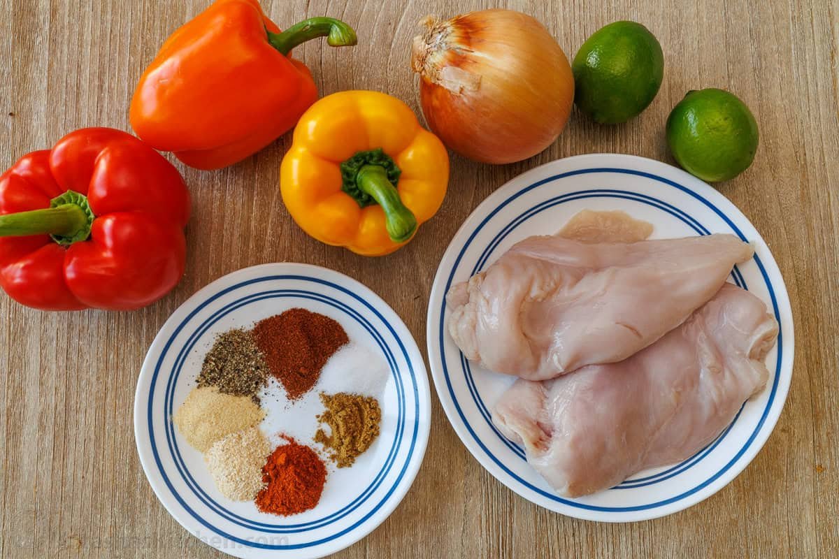 Sheet Pan Chicken Fajitas recipe packed with flavor. It's a crowd-pleasing, 30-minute, one pan meal that makes any weeknight meal a fiesta! ingredients for sheet pan fajitas including chicken, bell peppers, onion, lime, and homemade fajita seasoning