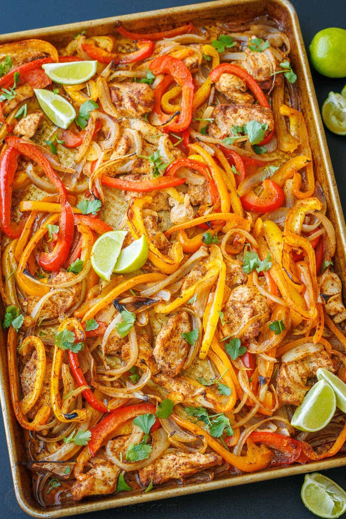Sheet Pan Chicken Fajitas recipe packed with flavor. It's a crowd-pleasing, 30-minute, one pan meal that makes any weeknight meal a fiesta! Chicken Sheet Pan Fajitas with peppers, lime wedges, chicken and homemade fajita seasoning