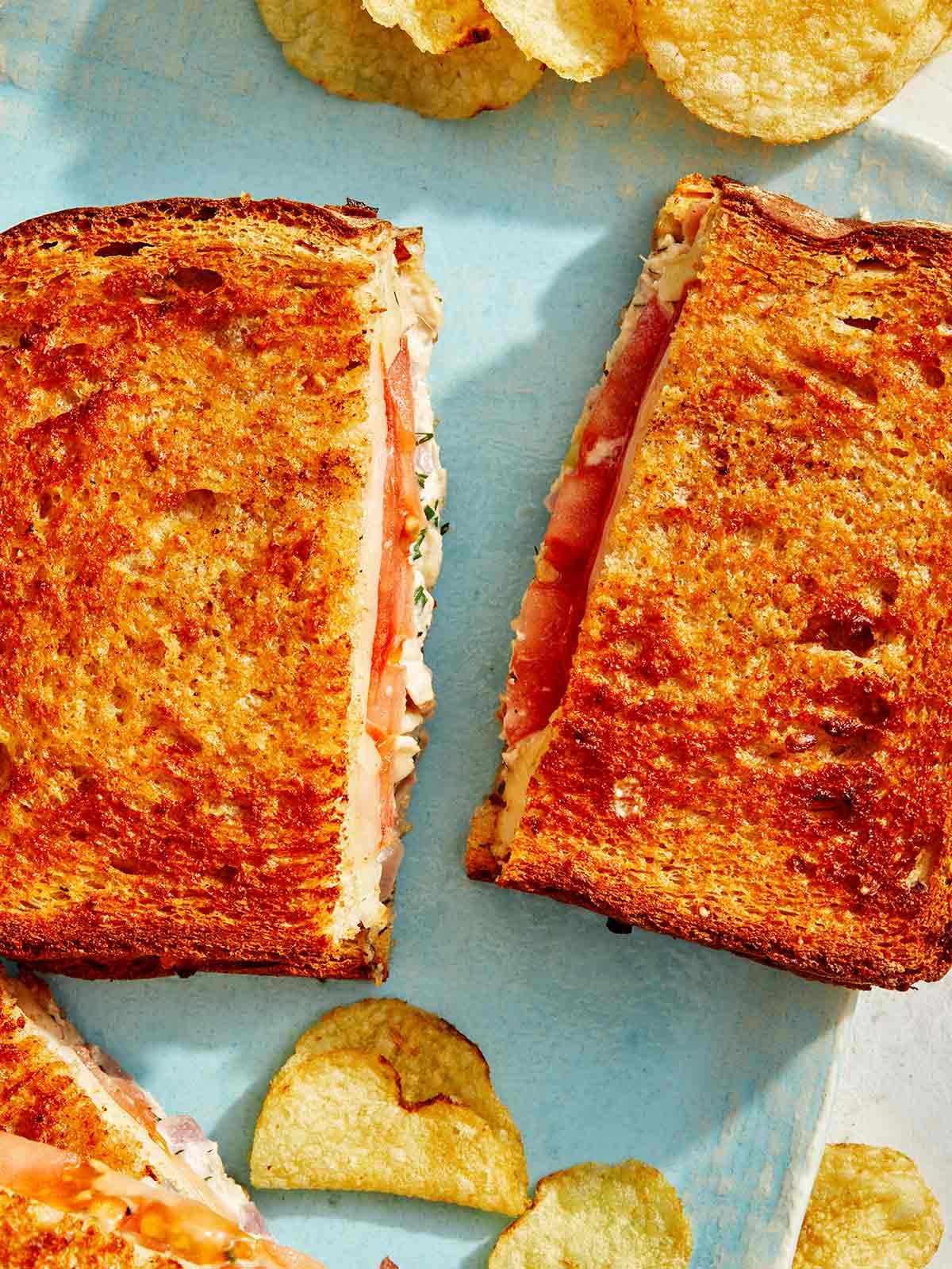 Air fryer tuna melt recipe cut with potato chips on the side.