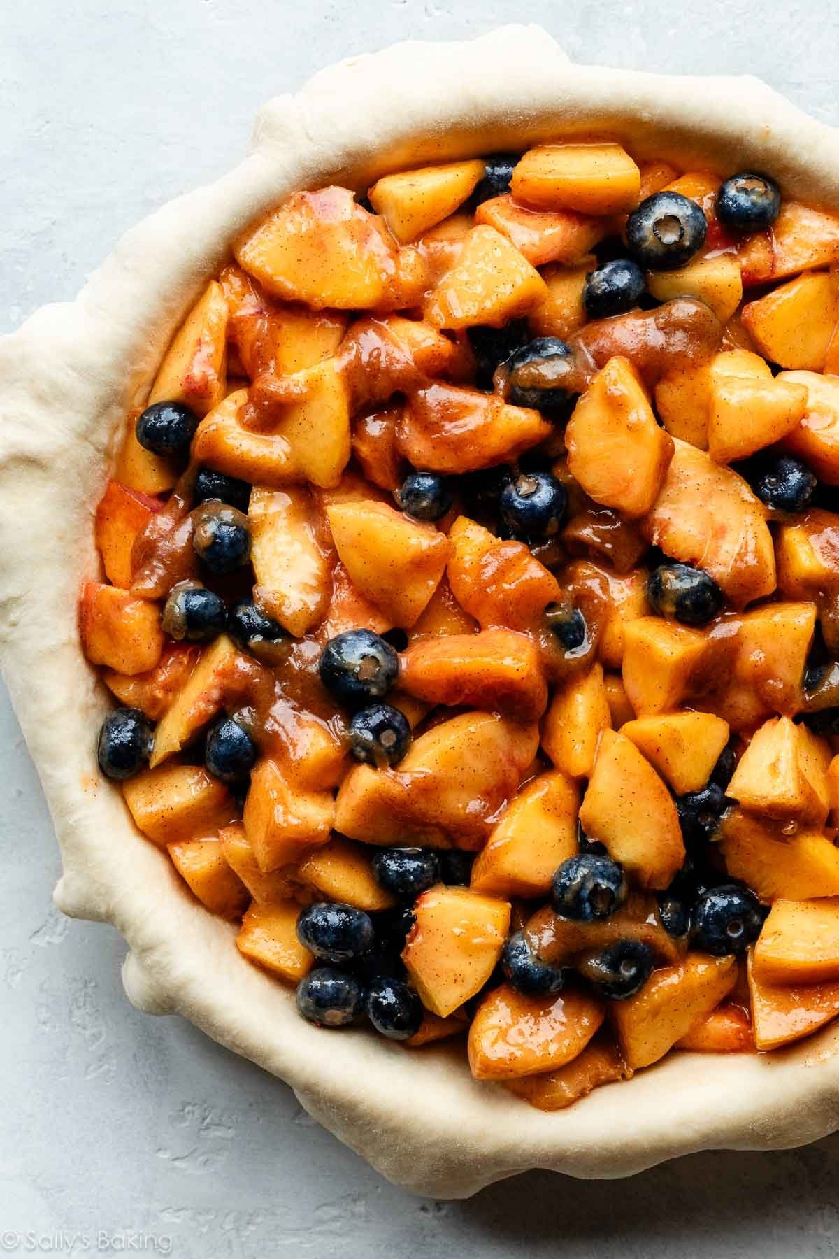 blueberries and peaches in bowl and shown again tossed with other filling ingredients.