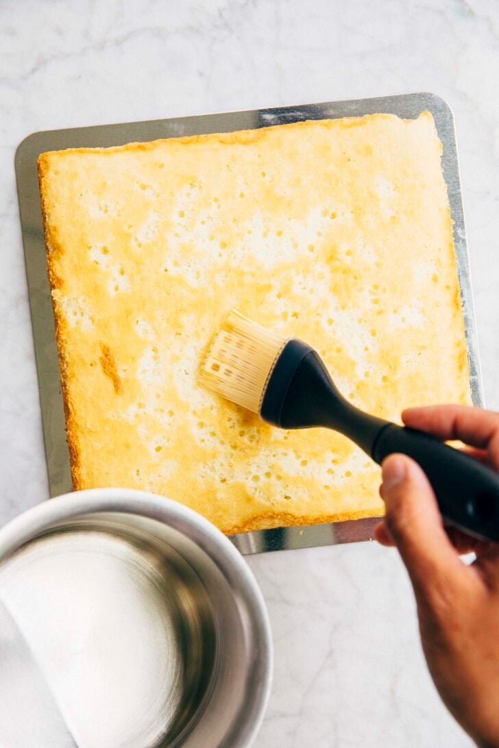 photo of Michelle from Hummingbird High soaking the first white almond cake layer with simple syrup