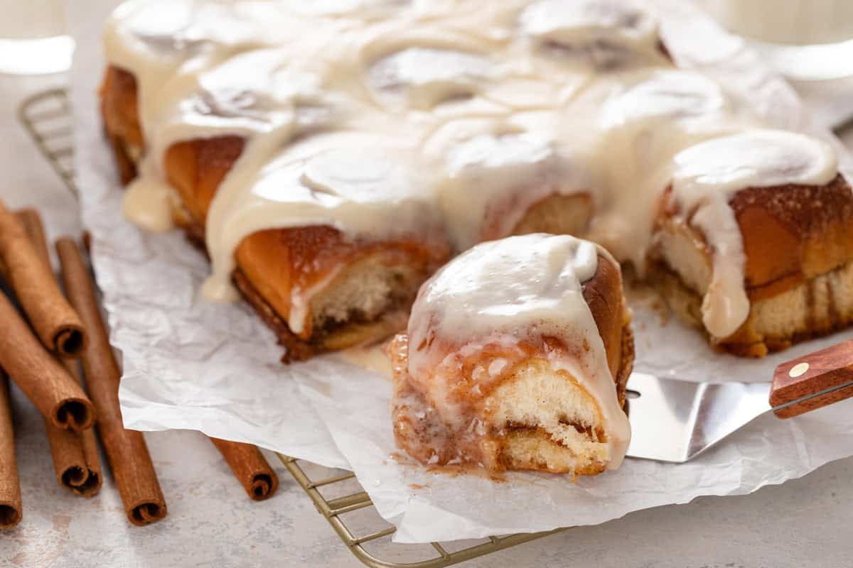 Cake server about to serve a cut hawaiian roll cinnamon roll.