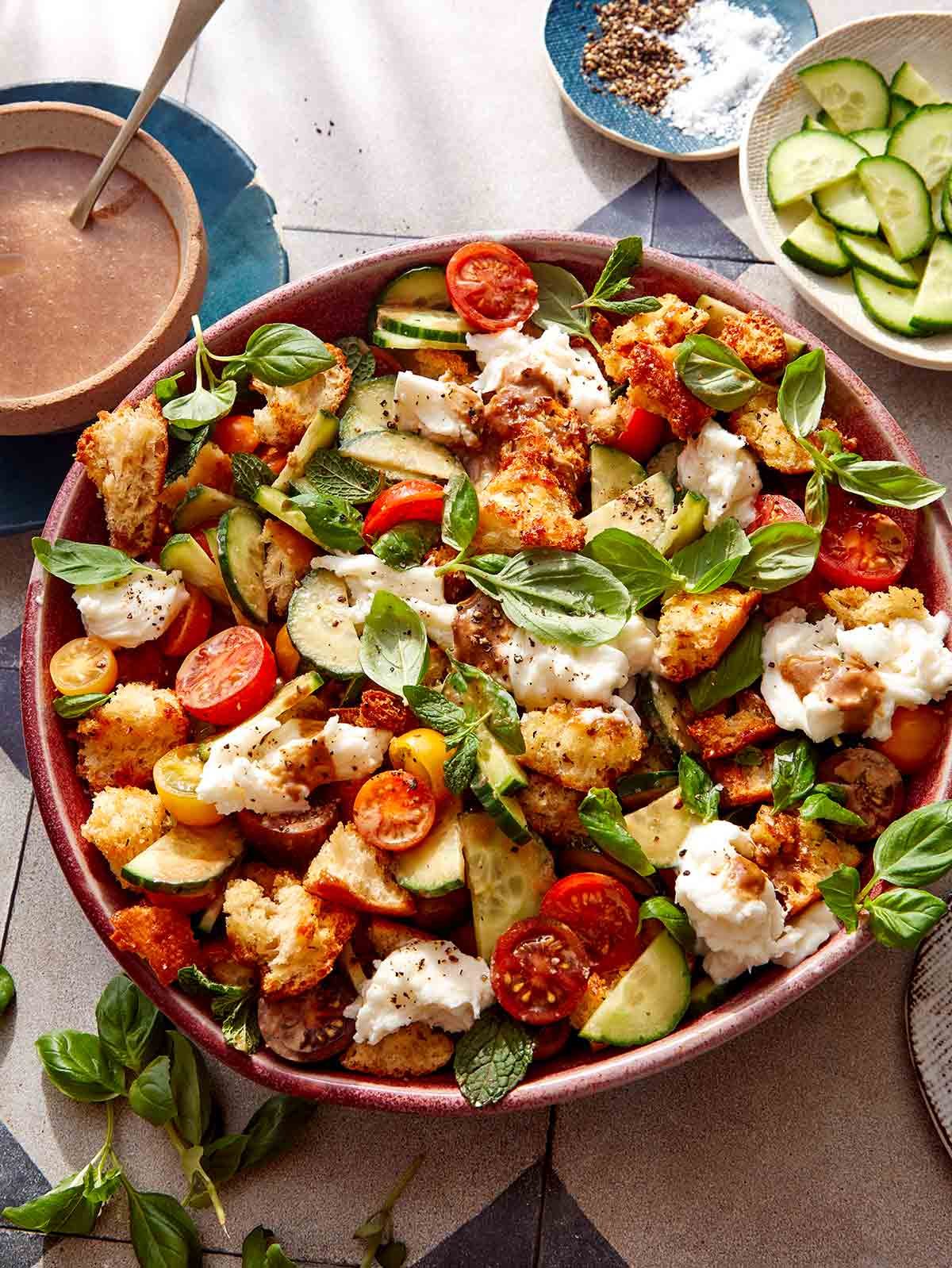 Panzanella salad in a bowl with balasmic vinaigrette next to it.