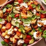 Panzanella salad in a bowl with fresh herbs on top.