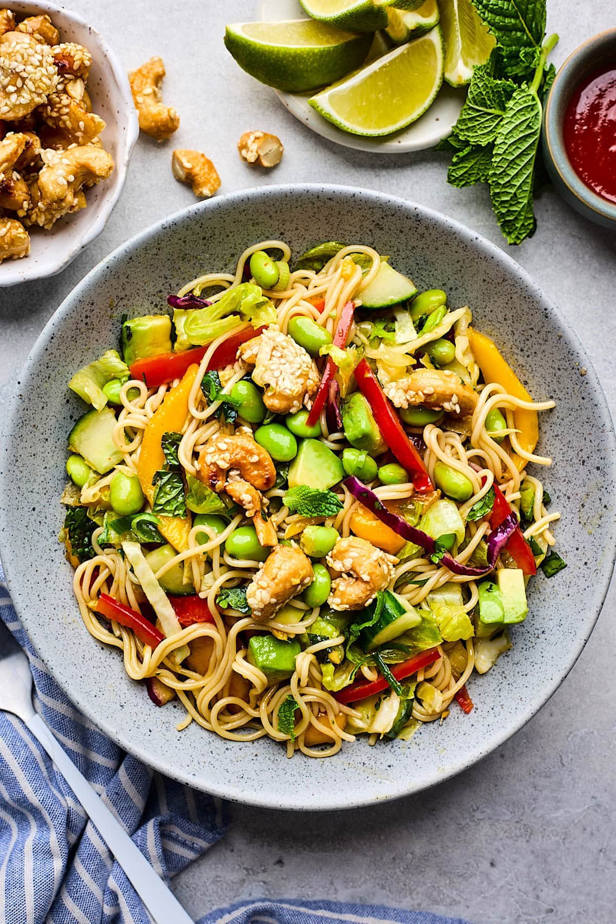 sesame noodle salad in bowl with colorful veggies and honey sesame cashews.