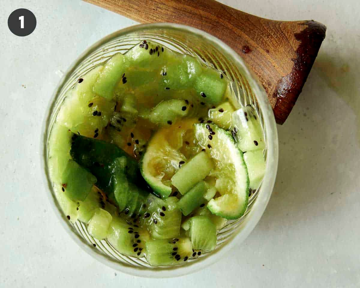 Muddled kiwis and limes in a drink glass. 