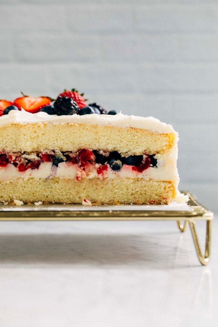 photo of berry chantilly cake sliced showing the layers of cake, fruit, and chantilly cream
