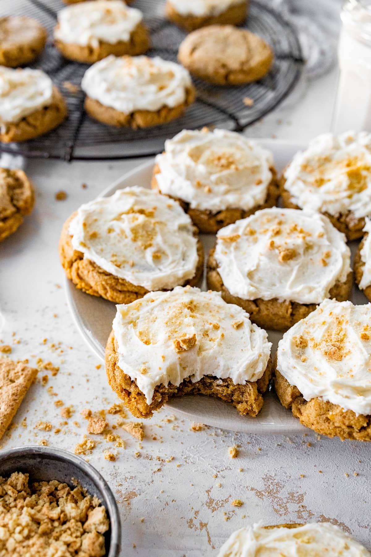graham cracker cookies with vanilla frosting on plate and one cookie with a bite taken out of it.