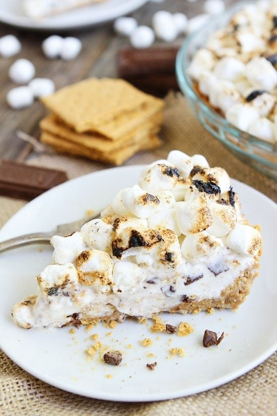 S'mores Ice Cream Pie Recipe on twopeasandtheirpod.com Graham cracker crust, vanilla ice cream with chocolate bar chunks, toasted marshmallows, graham cracker pieces, and topped with more toasted marshmallows! This is the ultimate S'mores dessert! S'mores Ice Cream Pie Recipe