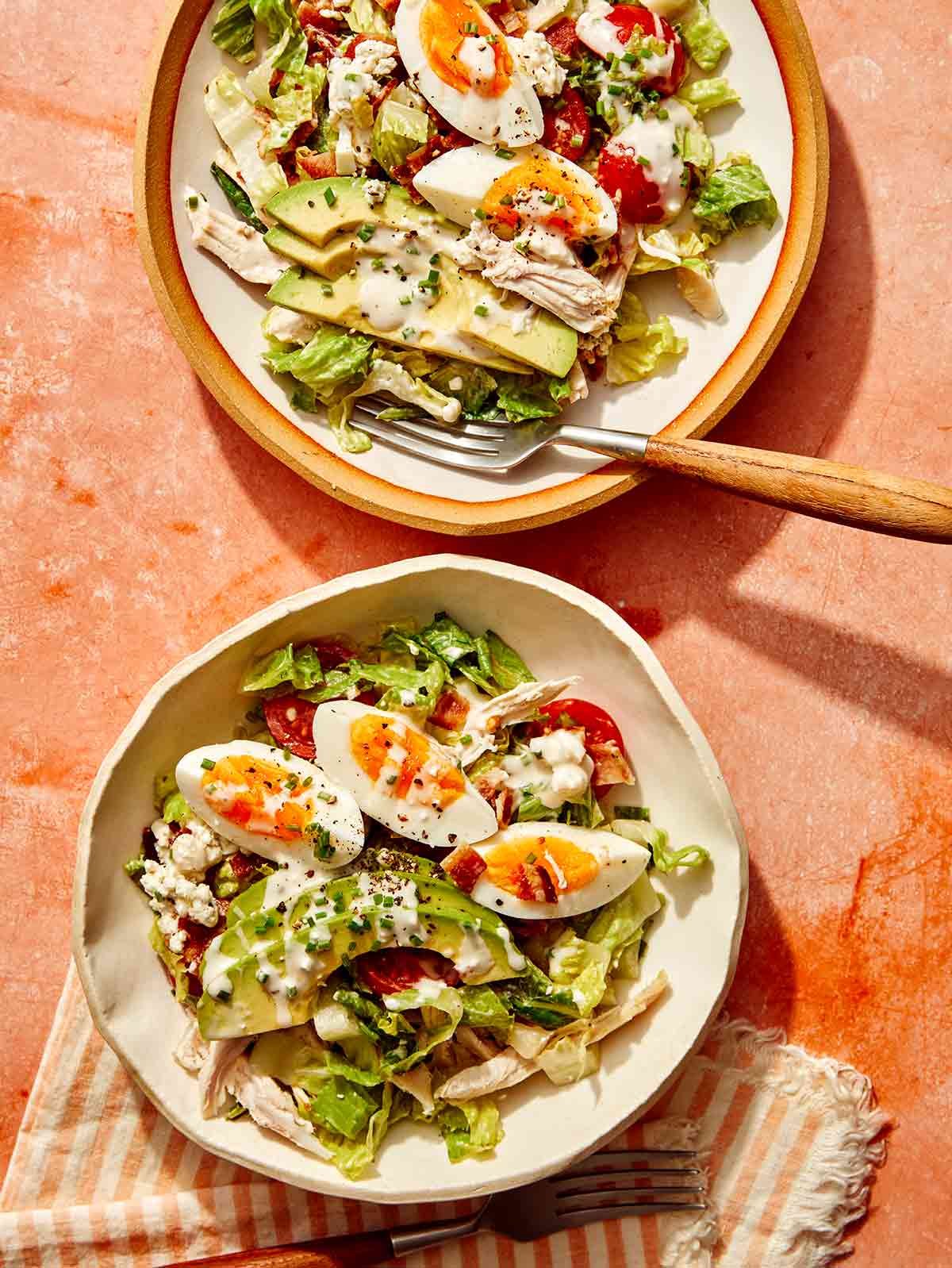 Two bowls of cobb salad ready to be eaten.