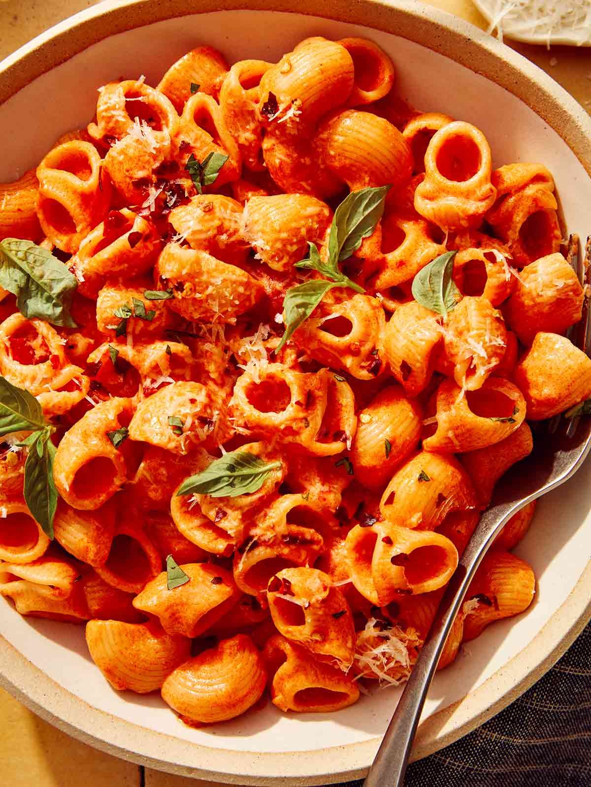 Spicy rigatoni in a bowl up close with a fork on the side.