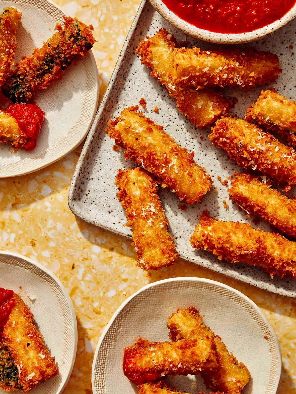 Fried zucchini on plates being eaten.