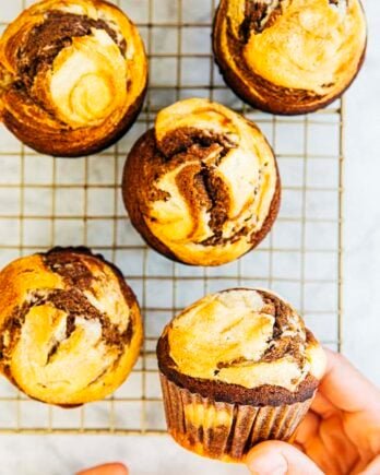 photo of hand holding pumpkin cream cheese muffin over gold wire rack