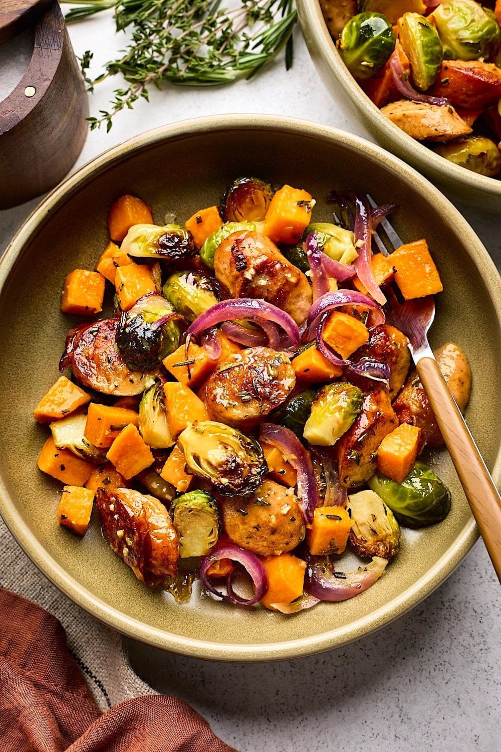 sheet pan sausage and vegetables in bowl with fork.