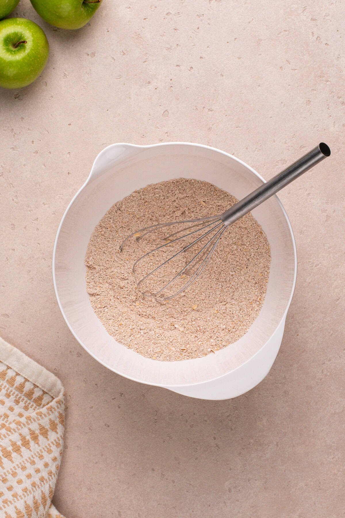 Dry ingredients for apple spice cookies whisked in a white bowl.