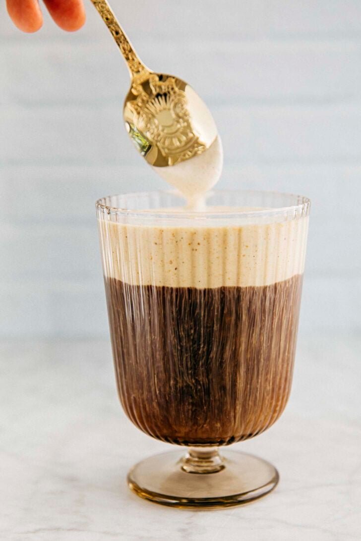 photo of michelle from hummingbird lifting a spoon from a glass of coffee with pumpkin cream cold foam