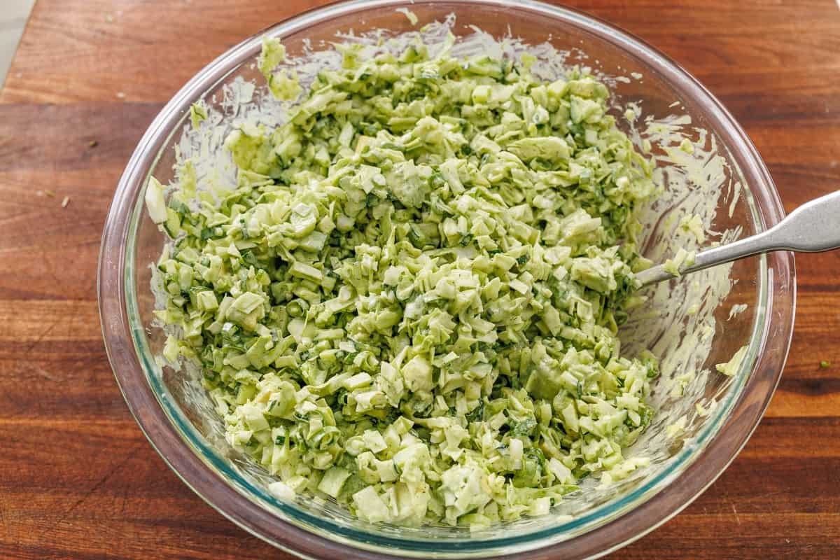 chopped cabbage and cucumber tossed with dressing in a clear bowl