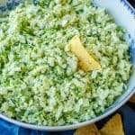 A corn chip dipped into a bowl of Green Goddess Salad in a white bowl
