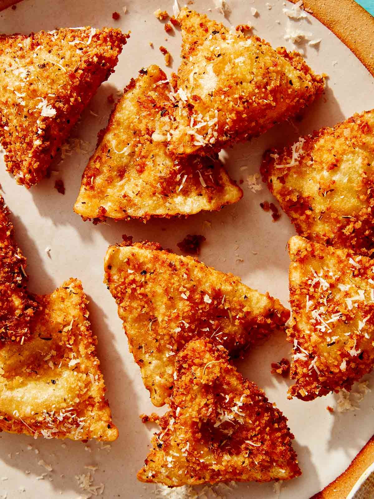 Close up on a plate of toasted ravioli topped with some parmesan.