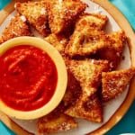 Toasted ravioli on a platter served with marinara sauce.