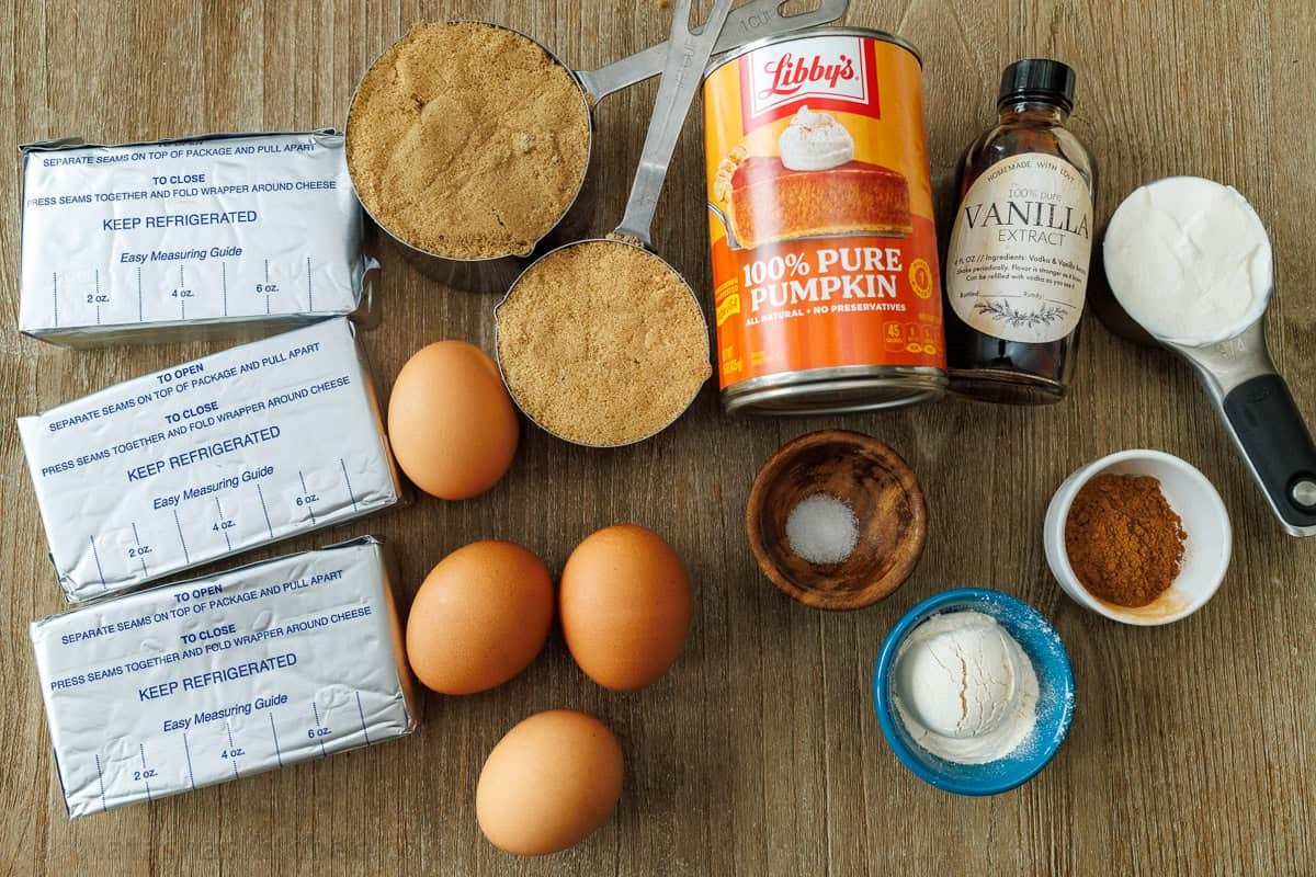 Ingredients for easy Thanksgiving dessert including cream cheese, eggs, brown sugar, graham crackers, canned pure, vanilla extract, salt, cinnamon, sour cream and flour