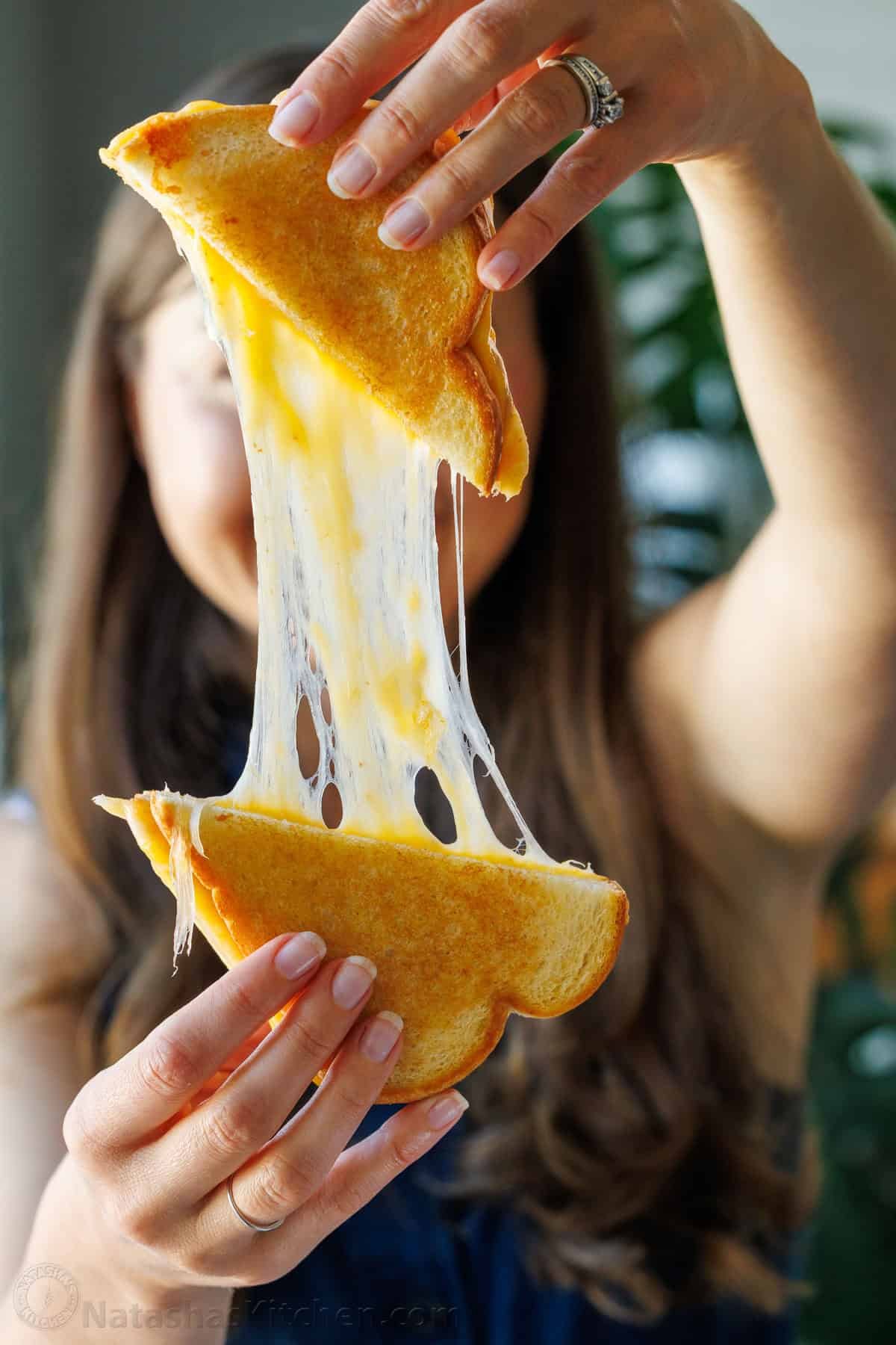 woman showing a Cheese-pull from a sliced sandwich