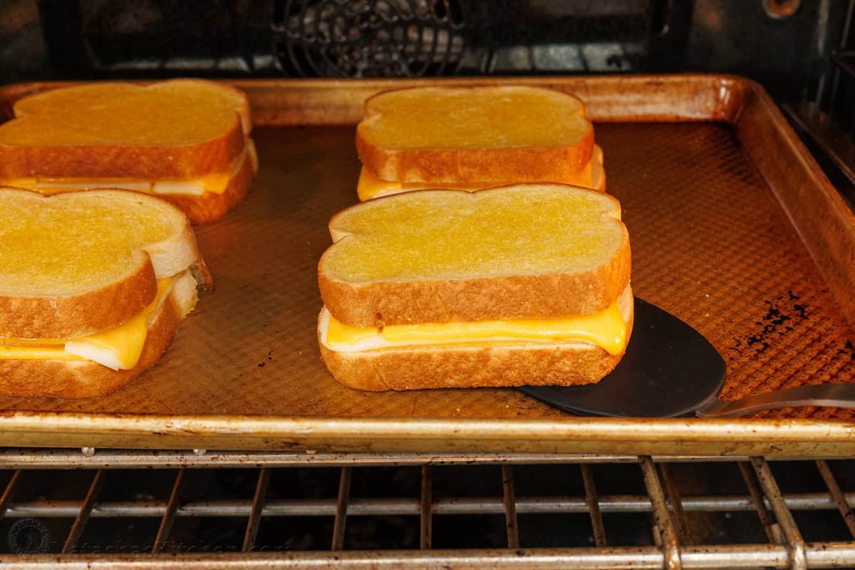 sandwiches lined up on a baking sheet to melt