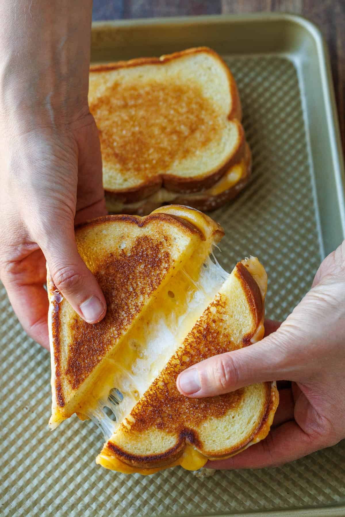 Two oven-toasted sandwiches on a cookie sheet cut in half