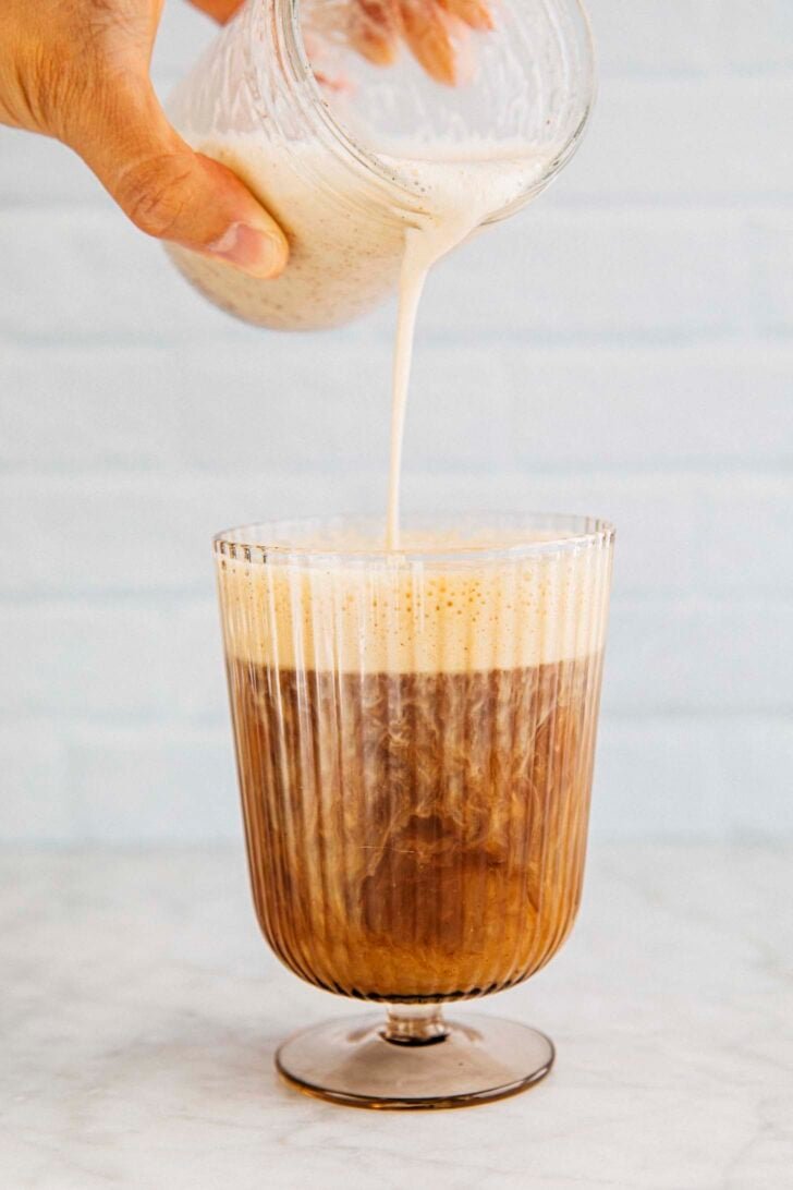photo of michelle from hummingbird high pouring pumpkin cream cold foam into a glass of coffee