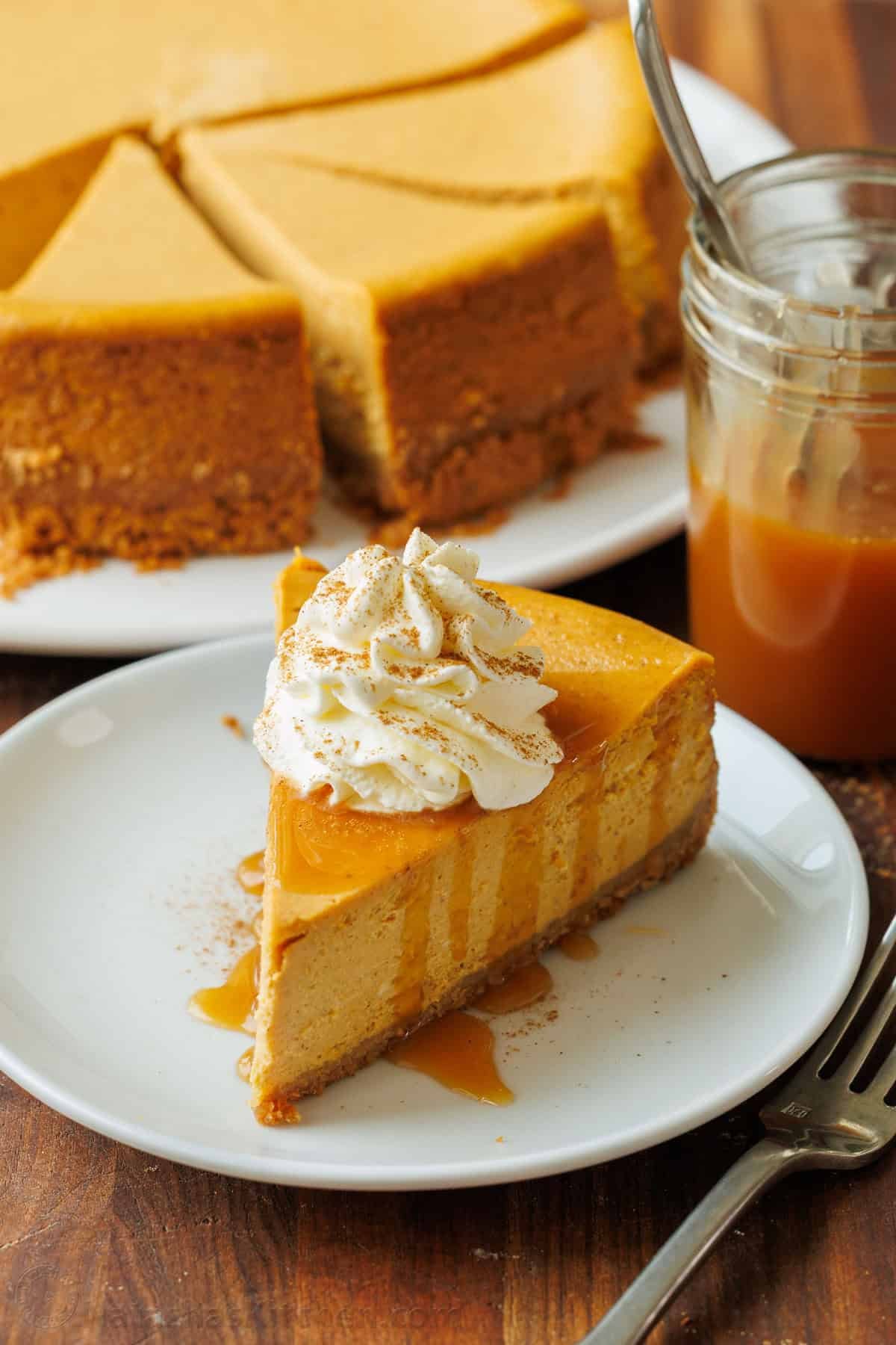 Pumpkin Cheesecake cut into pieces with one slice on a plate with caramel sauce drizzled on top