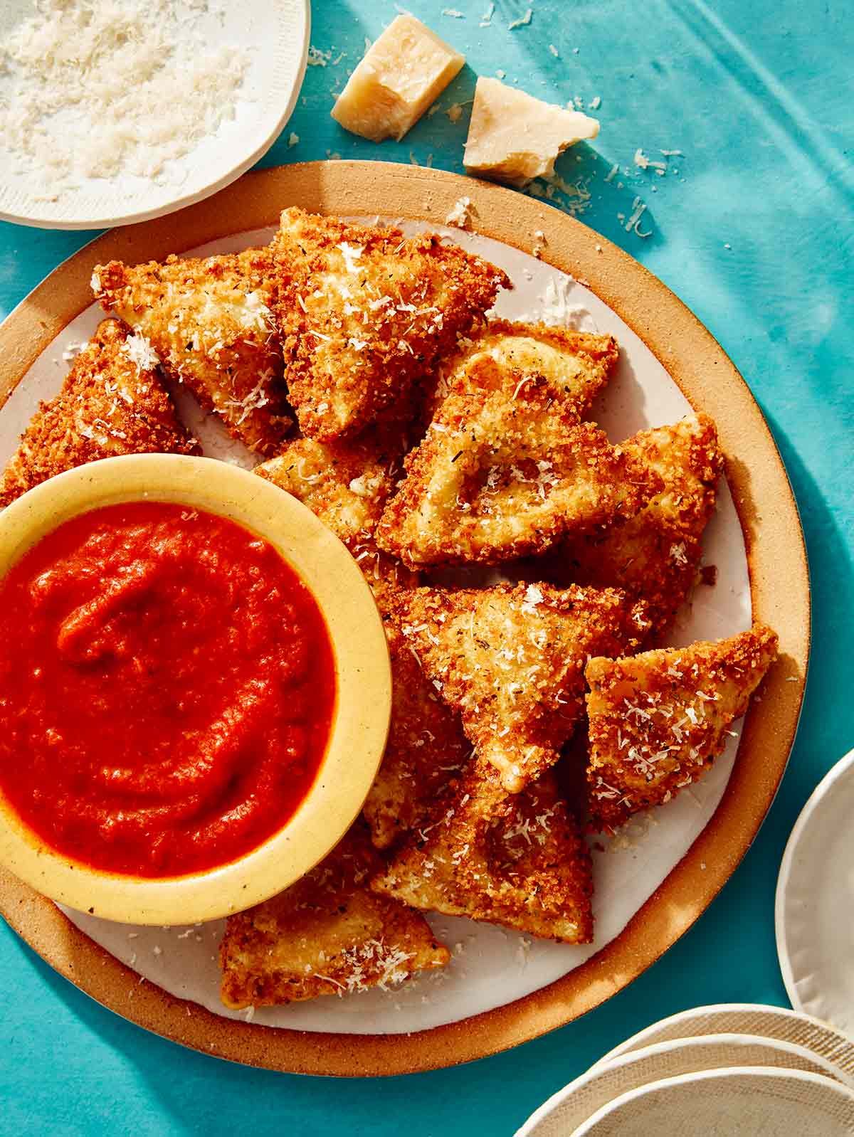 Toasted ravioli on a platter served with marinara sauce. 