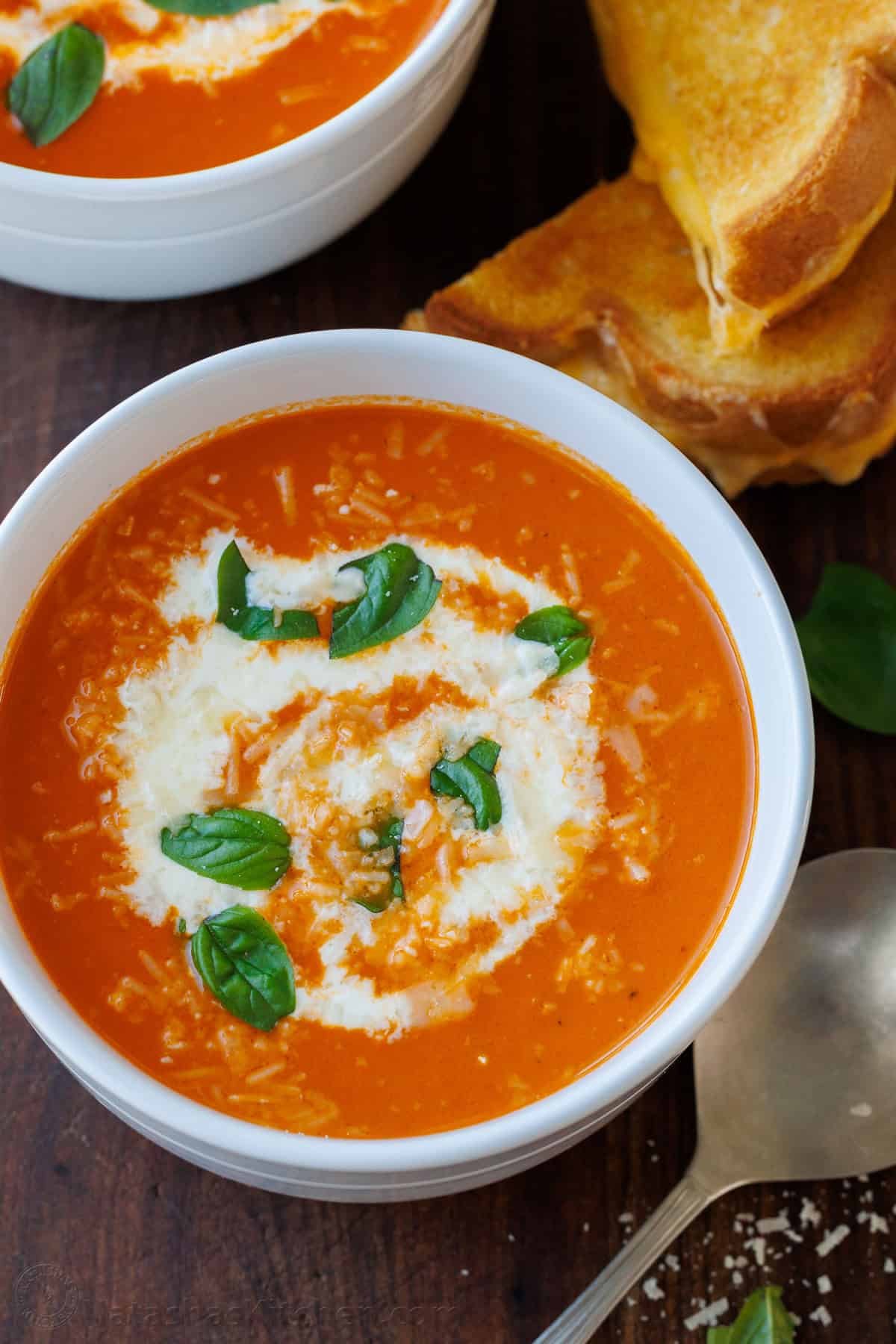 Roasted Tomato soup with Parmesan cheese and basil in a white bowl