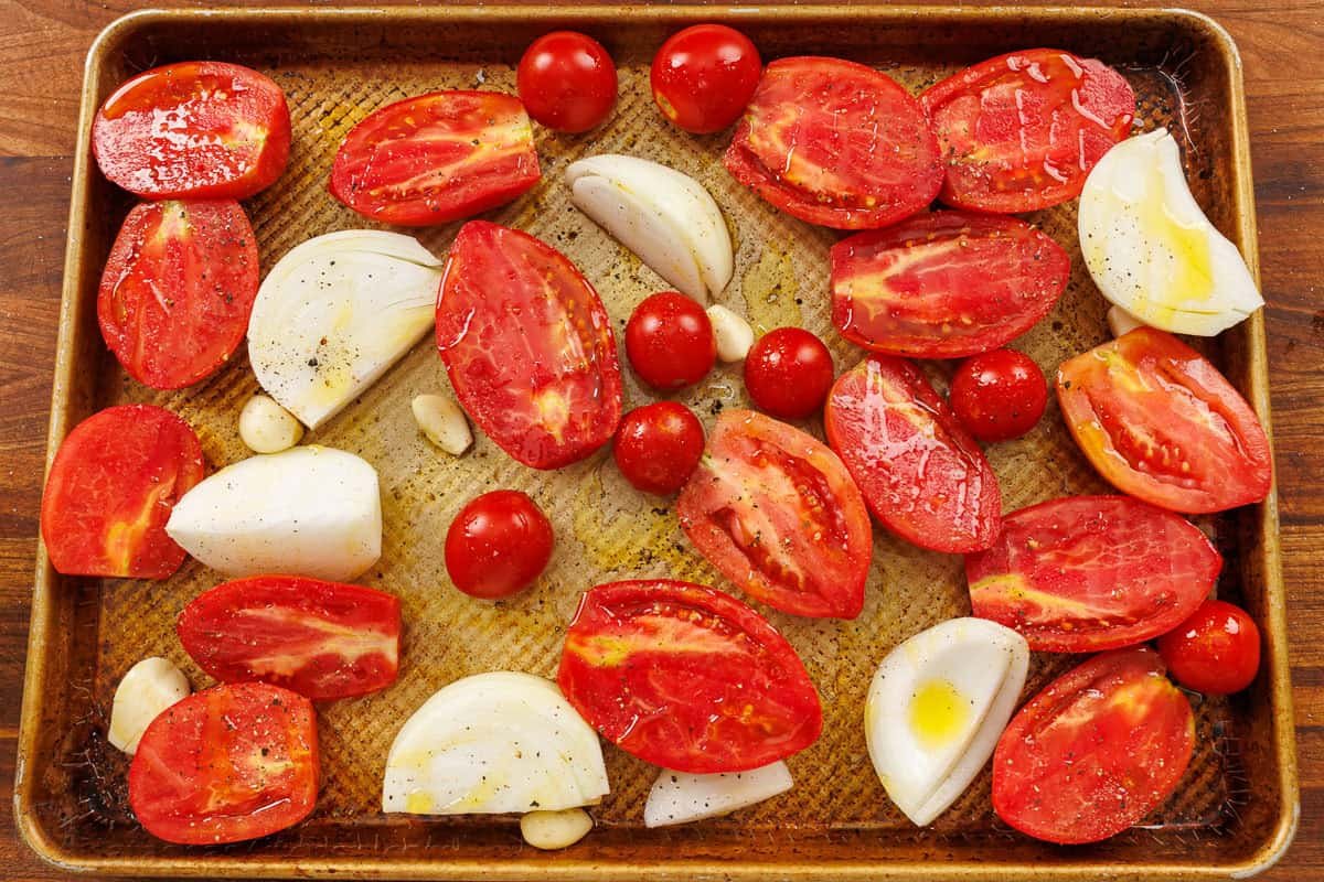 Tomatoes and onions on a sheet pan for roasting