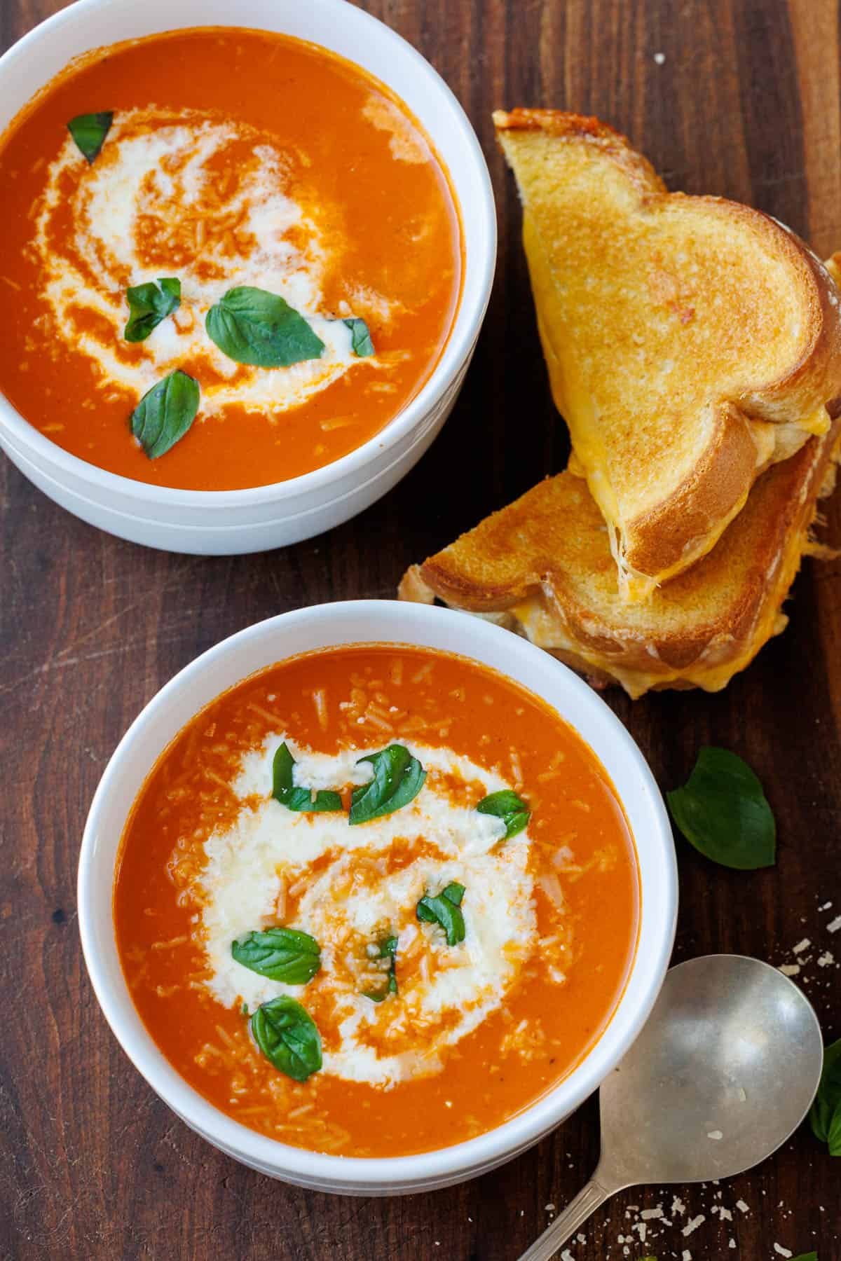 Nostalgic childhood dinner of Grilled Cheese served with bowls of Homemade Tomato soup on a wooden table