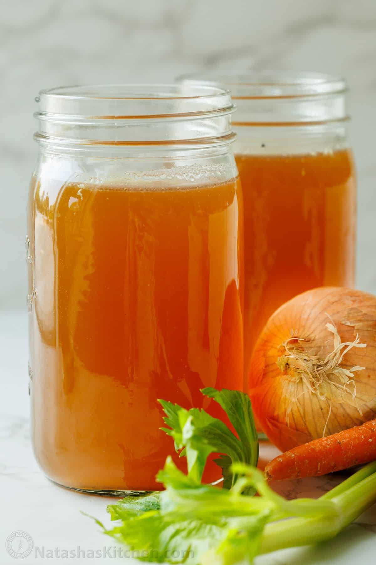 Mason jar of homemade bone broth with onion, carrot and celery