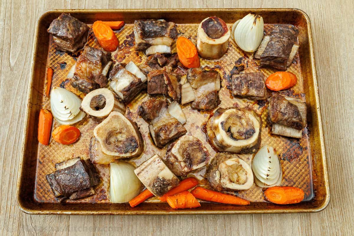 Roasted beef bones, meat and vegetables on a pan