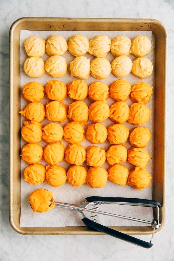 photo of 12 Sweetened Condensed Milk and 30 Thai Tea cookie dough balls scooped onto a gold quarter sheet pan